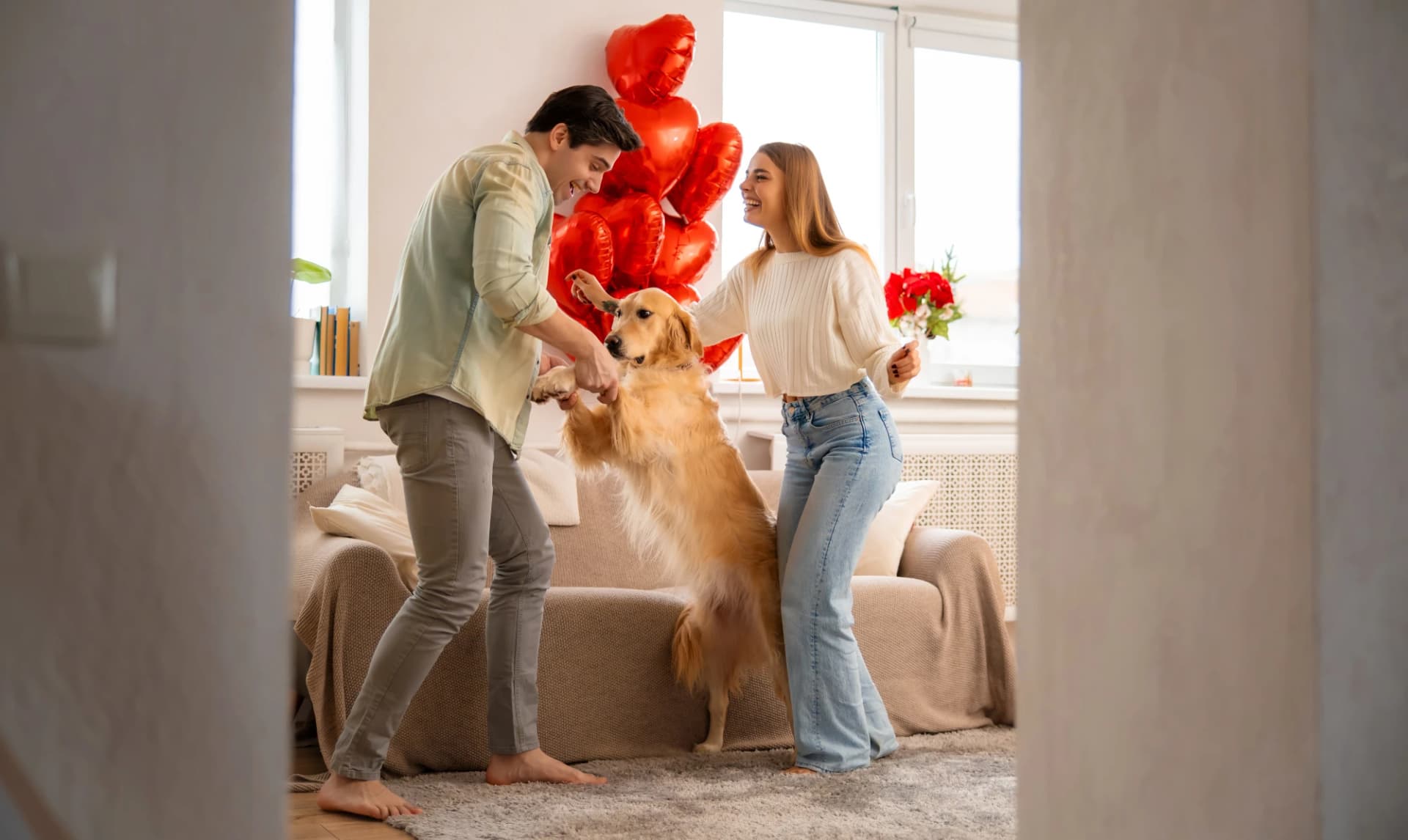 Joyful young couple dancing with their dog at home, celebrating Valentine’s Day together. Joyful young couple dancing with their dog at home, celebrating Valentine’s Day together.